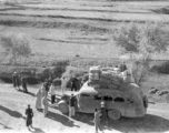 Long-haul bus in northern China during WWII, piled high with cargo. Note the wooden tires on the front, a consequence of war-time limits on rubber use.