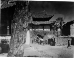 A village gate, with a temple to left with “太平乐事” written above door. During WWII.