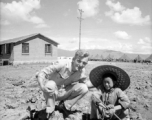 Luliang (China), Bert Krawczyk and a young boy at the air base at Luliang, ca. 1943-1945: "Bert Krawczyk at Luliang in Yunnan Province, China. This young Chinese boy was part of the thousands of local people from the town and surrounding area that worked at the air base. The Operations building to the left was constructed by the Chinese of mud brick. Tents in the background were hastily set up to house retreating American and Chinese soldiers after the loss of forward airfields in central China. The boy (ag