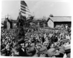 Burma Road dedication parade and ceremony in Kunming, China, on or around February 4, 1945, during WWII. Review of first convoy (or one of the first convoys) to reach China. Ranks of soldiers and civilians. Note movie camera filming on far right, and just below that, a couple of African-American officers.