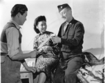 Chinese candymaker at the Russian bakery offering some of the now locally manufactured candy which is soon to be sold in US Army Post Exchanges, at APO 627, to Maj. Robert E. Envell. Sitting by is MME Wei Chen-ko, wrapping the peanut candy. Yunnan Province on December 15, 1944.   Photo by Pfc. Thomas F. Melvin.  Passed by Emanuel Goldberg.