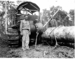 Bulldozer using cable choker to pull log through mud in Burma.  797th Engineer Forestry Company in Burma.  During WWII.