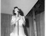 Singer at a USO show in Gushkara, India, during WWII.  The boxes in front of the band players are labeled 748th ROB (748th Railway Operating Battalion).