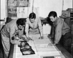 Men from the 21st Photographic Reconnaissance Squadron examine some photographs. In China, during WWII.