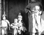 Local people in China: A poor elderly couple in a village watch over young children. During WWII.
