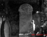 During WWII a boy stands in front of a stone tablet in the entry area of a temple or other building, probably in Yunnan province.