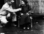 S/Sgt. Steve Wasylyshyn, 279 Garfield St., Johnstown, Pa., inspects jewelry an 82 year old Chinese woman has again brought out now that the Japanese have left her village.  She explained that she hid them when the Japanese first came and has kept them that way through all of their occupation.