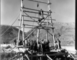 A pole driver, built on-site, is employed by workers in SW China to drive bridge supports into the ground. During WWII.